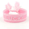 Roze gevlochten polsband met witte LUCKY-letters en decoratieve bijpassende kwastjes - Zilveren Lucky Stijl