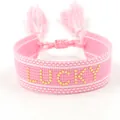 Roze geweven armband met gouden stip LUCKY belettering en decoratieve franjes en kwastjes - Gouden Lucky Stijl