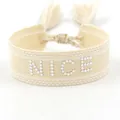 Handwoven beige tassel bracelet featuring NICE logo in 3D white rivet letters - Silver NICE Style