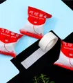 Macro shot of double-sided balloon glue dots roll and individual red and white packaging bags - Balloon Glue Dots