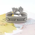 Detail eines grauen gewebten Armbands mit silbernen Sternnieten und Quasten - Grau Rosa Gestreift (3#)