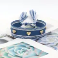 Close-up of handmade woven blue and white bracelet with three golden heart-shaped studs - Gold Heart Rivets / Blue and White Woven (H-G-001)