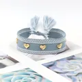 Detail of light blue woven bracelet with golden heart-shaped studs and tassel finish - Gold Heart Rivets / Baby Blue (H-G-024)