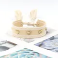 Detail view of woven beige heart friendship bracelet with tassels and golden heart charms - Gold Heart Rivets / Beige White Stripes (H-G-023)