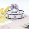Primer plano de pulsera de amistad tejida con tachuelas de estrella plateada y borlas - Lila Blanco Geo (33#)