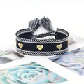 Close-up of a black woven friendship bracelet featuring golden heart rivets and tassels - Gold Heart Rivets / Black and White Dotted (H-G-010)