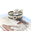 Detalle macro de la pulsera tejida bohemia con botón de presión plateado y flecos - Beige Negro (32#)