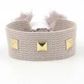 Bracelet tissé beige réglable avec clous pyramides dorés et glands sur fond blanc - Beige Gris