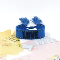 Detail of navy blue woven LOVE bracelet with yellow stitching and decorative tassels - Style 43 White Flamingo Leaf