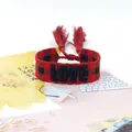 Close-up of woven love bracelet with red and black tartan pattern and fringe details - Style 50 Navy Red/Green Flower