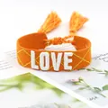 Detailed close-up of orange braided bracelet with white LOVE embroidery and tassels - 26#