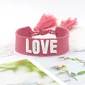 Detailed macro view of pink fabric bracelet featuring 3D white embroidered LOVE text and tassels - 28#