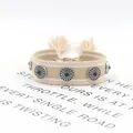 Detalle de pulsera boho tejida con remaches plateados y cuenta azul en tarjeta blanca - Beige (13#)