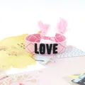 Pink woven friendship bracelet with black LOVE embroidery and tassel details - Style 56 Yellow Daisy