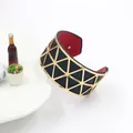 Detail of wide gold hollowed cuff bracelet featuring red inner lining and geometric pattern - Gold Frame Black Red Leather
