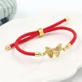 Bracciale a corda intrecciata rossa con ciondolo a farfalla dorata su vassoio in ceramica - Stile Farfalla Dorata