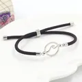 Detail van een verstelbare donkerbruine gevlochten armband met zilveren golfbedel - Golfpatroon Stijl / Staal Kleur + Bruin
