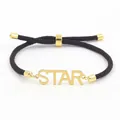 Detail van verstelbare bruine gevlochten armband met een gouden STAR-bedel - STAR-letter / Donkerbruin
