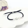 Detail van verstelbare zwarte geweven armband met zilveren Love oneindigheidsteken - Staal + Zwart