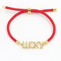 Dettaglio del bracciale in corda rossa di Milano con ciondolo Lucky dorato e chiusura regolabile - Stile Lettera Lucky Oro