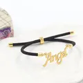 Dettaglio del ciondolo dorato Angel su un braccialetto in corda intrecciata marrone - Stile Lettera Angel Oro
