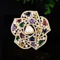 Close-up of golden camellia brooch with colorful gemstones, zircons, and a center pearl - Multicolor Camellia Style