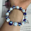 Close-up detail of blue evil eye beaded elastic bracelet with floral ceramic beads on wrist - Blue and White Porcelain Flower Evil Eye Style (Style-4)