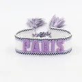 Detailed macro of woven friendship bracelet with purple PARIS embroidery and tassels - Purple PARIS Embroidery Tassel / Purple PARIS