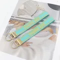 Close-up of mint green embroidered CHEERS 2025 woven keychains with gold metal rings - Mint Green Embroidery Style / Green CHEERS 2025