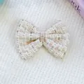 Macro shot of tweed bow hair clip with faux pearls and rhinestones on plush background - One Size / Beige