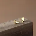 Orecchini a perno a forma di pesce d'oro minimalisti con zirconi su legno scuro - Oro rosa