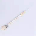 Detailed macro view of wooden pacifier clip with natural beads and metal fastener - White