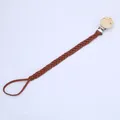 Detail der handgewebten braunen Schnullerkette mit rundem Naturholz-Clip aus Holz - Braun