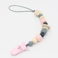 Detail of pink silicone beads and heart-shaped wooden beads on a baby pacifier clip - Pink