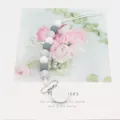 Silicone pacifier clip with white and marble grey beads on a floral card display - Gray