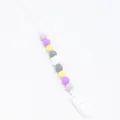 Close-up of silicone pacifier clip with colorful beads and secure plastic clasp attachment - White