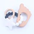 Detail van houten babybijtring met siliconen kralen ster en beukenhouten speelgoed - Witte Voetafdruk Stijl