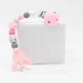 Detailed view of silicone pacifier clip with pink crown and marble beads on a white stand - Pink