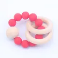 Close-up of baby teether bracelet with red silicone beads and natural wooden rings - Red