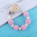 Chupetero de madera y cuentas de ganchillo rosa sobre fondo de madera estilo vintage - Rosa