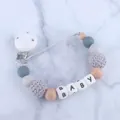 Detail eines Schnullerketten-Clips mit Silikon- und Holzperlen sowie BABY-Buchstaben - Grau