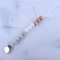 DIY baby pacifier clip with marble grey and natural beech wood beads on blue background - White