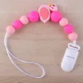 Rosa Silikon Schnullerkette mit Flamingo Perlen auf hellem Holzhintergrund - Flamingo - Rosa