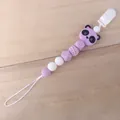 Detalle de sujetachupetes de silicona violeta con cuenta de panda sobre fondo de madera - Púrpura