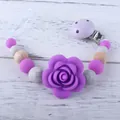 Schnullerkette aus Silikon mit lila Perlen und Rose auf weißem Holz Hintergrund - Lila