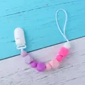 Baby pacifier clip with purple and pink silicone beads on a wooden background - Purple Character