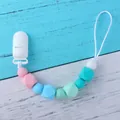 Baby silicone pacifier clip with macabre beads and white clip on wood background - Pink Style