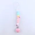 Detail of macaron-colored silicone pacifier clip with purple bells and plastic clip - Pink