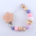 Detailed close-up of a silicone pacifier clip with natural wooden beads and knitted balls - Flower Style