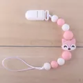 Macro detail of a pink silicone baby pacifier clip with a cartoon fox bead on wood - Fox Pink